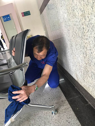 保洁员孙师傅正爬在地上仔细擦拭椅腿。保洁员们的辛勤劳动为医院的工作人员和就诊患者创造了良好的环境。.jpg